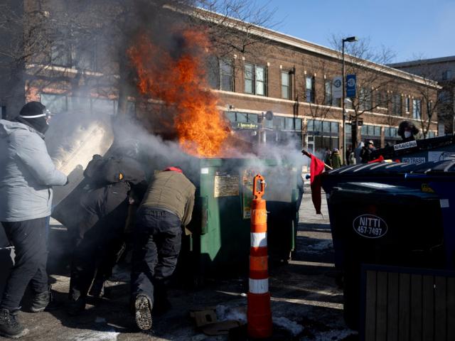 Protesters push an a burning dumpster toward law enforcement near the site of the fatal shooting of 37-year-old Alex Pretti by federal agents in Minneapolis on Saturday, Jan. 24, 2026. (Ellen Schmidt/MinnPost via AP)