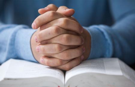 Hands folded on Bible