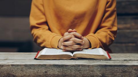 open bible clasped hands