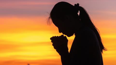 silhouette of woman praying outside