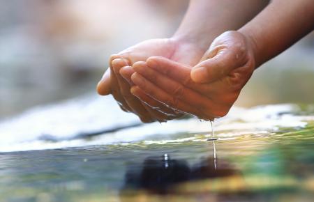 a person holding water from a stream